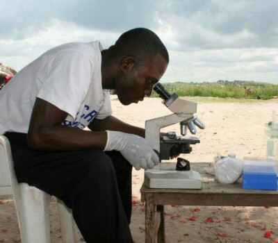 jossdinangamuzudianalysingasampleunderthemicroscopeinthevicinityofmbujimayiphotoinstituteoftropicalmedicineantwerp